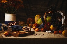 Closeup Of A Basket With Fruits And Vegetables On A Table With Flower Vase. Still Life.