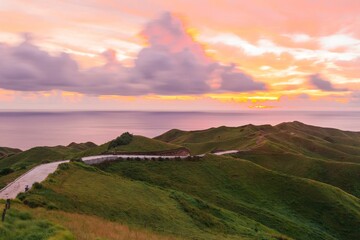 Walkway on the green hills under the pink sunset sky in Batanes