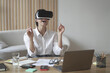 © VK Studio - Lady entrepreneur in VR headset sitting at desk at home office interacting with 3d visualization