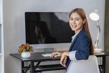 Wall Mural - Asian accountant sitting at his desk turn around and smile financial concept