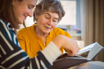 Old woman with her granddaughter look at family photos.