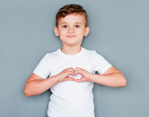 Wall Mural - Portrait of happy boy with a heart shape isolated on gray background