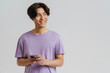 Young asian smiling boy in violet t-shirt holding phone