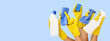 © ronstik - hand with yellow rubber glove holding cleaning supplies on blue background. banner with copy space