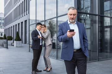 two colleagues are gossiping at background behind the boss. workmate about bullying problem at work 