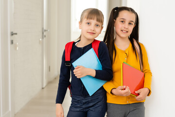 Wall Mural - Two little schoolgirls speaking and sharing secrets. Education, fashion, friendship concept.