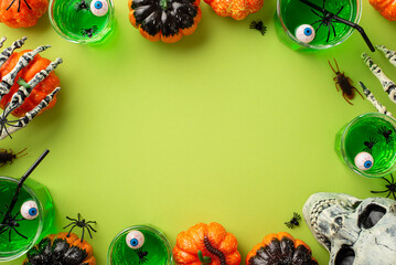 Halloween concept. Top view photo of green floating eyes punch in glasses skull skeleton hands spiders pumpkins and insects on isolated light green background with empty space in the middle