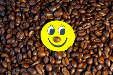 Yellow smiley on the background of roasted coffee beans.