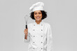 cooking, culinary and people concept - happy smiling female chef in toque with whisk over grey background