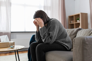 Wall Mural - mental health, psychological problem and depression concept - stressed woman with sedative medicine or painkiller on table having headache at home