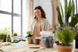 © Syda Productions - people, gardening and housework concept - happy woman in gloves planting pot flowers at home
