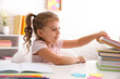 © New Africa - Cute little girl with books doing homework at table