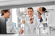 © Syda Productions - science, work and people concept - international group of happy scientists celebrating success and showing thumbs up in laboratory