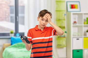 Wall Mural - childhood, gaming and leisure concept - unhappy boy in red polo t-shirt with gamepad playing video game over home room background