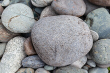 Large Stones Of Different Shapes On The Riverbank Close-up. There Are A Lot Of Small Stones Nearby.