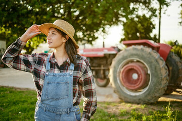 Poster - Farm, tractor and a woman in a hat in nature or field farming food, fruits and vegetables. Agriculture and natural environment with farmer in the countryside in the summer sun working on harvest