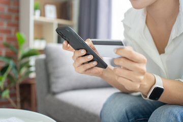 Close up of young woman hold smartphone and credit card make purchase on internet, new technology concept