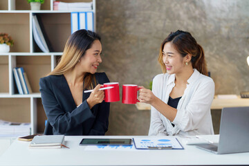 Wall Mural - Two young Asian businesswomen join together for coffee and work discussion and share their job descriptions and job description in making new product for the company.