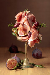 Wall Mural - Prosciutto with figs, rosemary, and red olives on a old wooden table.