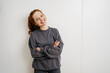 © contrastwerkstatt - young redhead woman stands laughing with folded arms in front of white wall