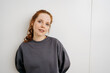 © contrastwerkstatt - young redhead woman in front of a white wall and looks promptly into the camera