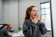 © contrastwerkstatt - young redhead woman looks scared in office