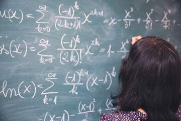 Wall Mural - Female student or teacher in the classroom writing on chalkboard mathematical equations