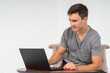 © Михаил Таратонов - A young man smiles and enthusiastically types while sitting in a chair on a laptop on a white background