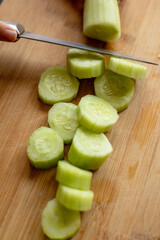 Wall Mural - cutting cucumber at home on wooden board close up