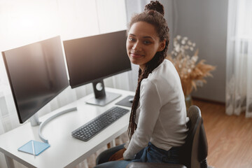 Wall Mural - portrait of young attractive positive woman sits in bright room at desk with computer monitors