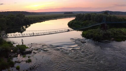 Wall Mural - Eine Hängebrücke über einen Fluss in Russland bei Sonnenuntergang.