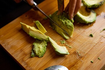 Wall Mural - cutting avocado on wooden board close up at home