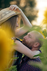 Wall Mural - Young romantic couple in sunflower field in sunset