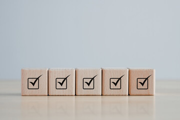 Checklist Survey and assessment. Quality Control. Goals achievement and business success. Check mark icon on wooden blocks.