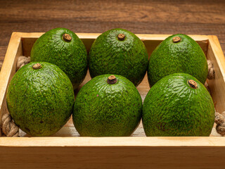 Wall Mural - Close-up of avocados fruit in a wooden tray on a wooden table