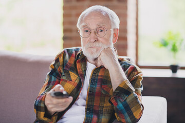 Sticker - Photo of sad bored grandparent white hair switch tv channels hold remote controller dressed casual plaid clothes sit sofa indoors flat room