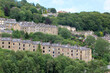scenic view of rows of typical tall stone houses between hillside trees in hebden bridge west yorkshire