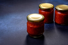 Homemade Hot Tomato Sauce Adjika In Jars. Tomatoes, Chilli Pepper, Garlic And Herbs