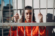© primipil - Young woman in orange suit behind jail bars. Female in colorful overalls portrait. Law and justice concept