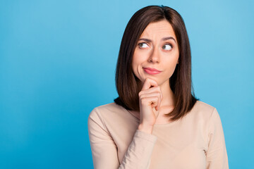 Wall Mural - portrait of pretty minded girl arm touch chin look empty space hesitate isolated on blue color backg