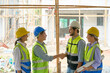 © bank215 - Two Team of foreman shake hand and join group to working with rainy day on construction building site