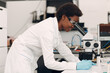 © primipil - Scientist african american woman in gloves working in laboratory with electronic tech instruments and microscope. Research and development of electronic devices by color black woman.