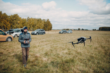 Wall Mural - Man pilot controlling quadcopter drone with remote controller pad.