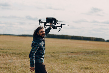 Wall Mural - Man pilot holding quadcopter drone in hands at outside field