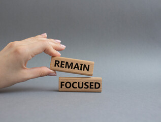 Remain focused symbol. Concept words Remain focused on wooden blocks. Beautiful grey background. Businessman hand. Business and Remain focused concept. Copy space.