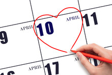 A Woman's Hand Drawing A Red Heart Shape On The Calendar Date Of 10 April. Heart As A Symbol Of Love.