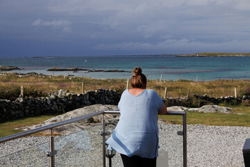 Poster - woman looking out from her patio onto the sea.