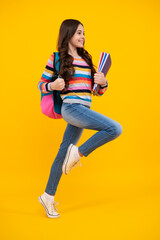 Canvas Print - School girl hold copybook and book on yellow isolated studio background. School and education concept. Teenager girl in school uniform. Happy teenager, positive and smiling emotions of teen girl.