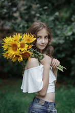 Young Girl With A Bouquet Of Sunflowers Stands Sideways