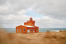 Lighthouse On Grassy Shore Of Sea